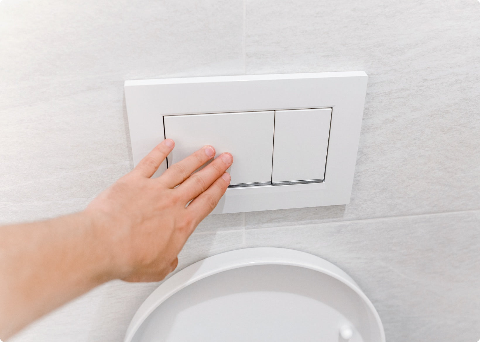 Hand drückt Knopf für Spühlkasten.